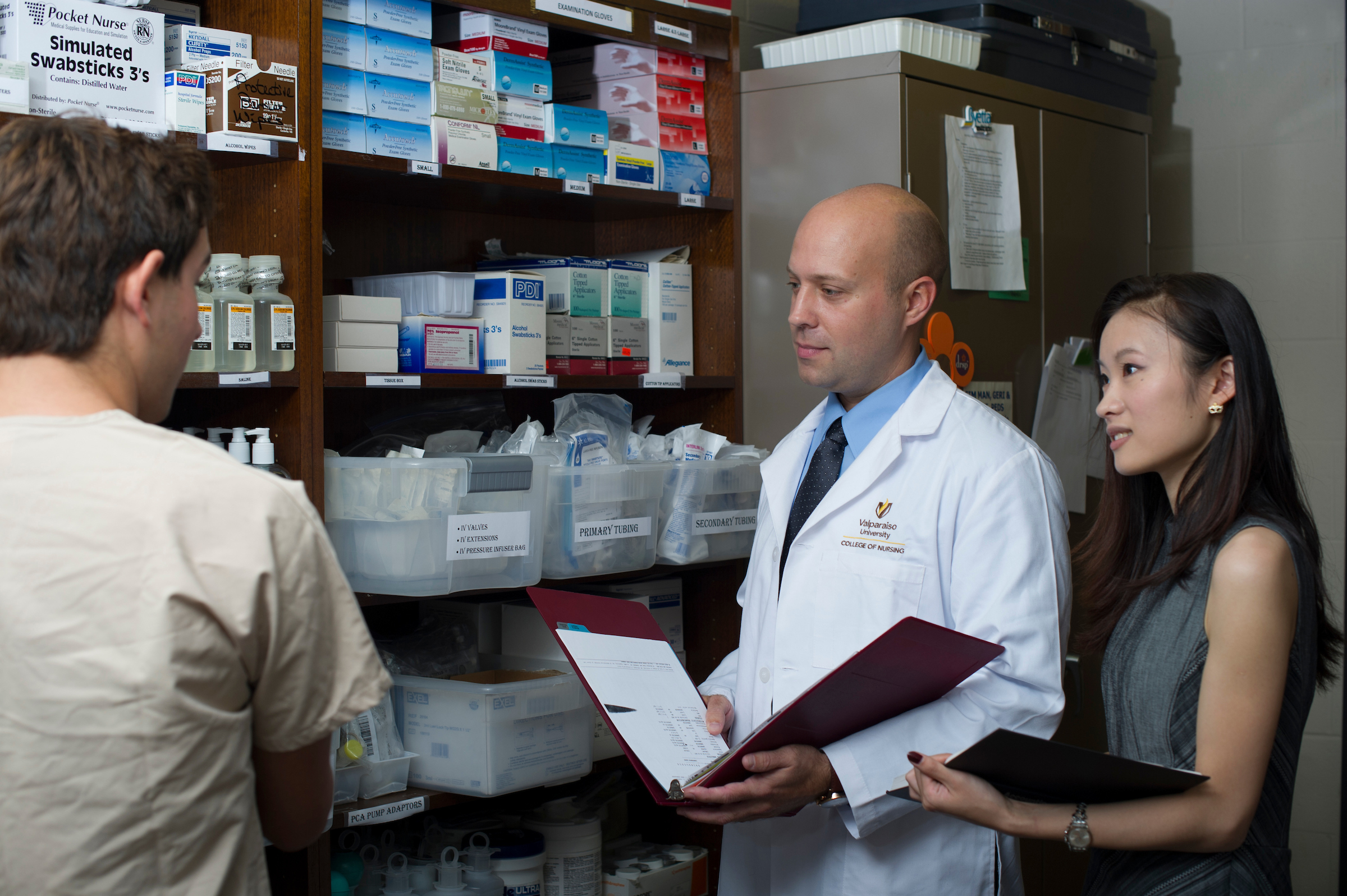 two healthcare professionals working with another worker